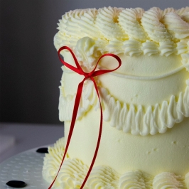 Tarta decorada con topper de lazo de cinta roja PME